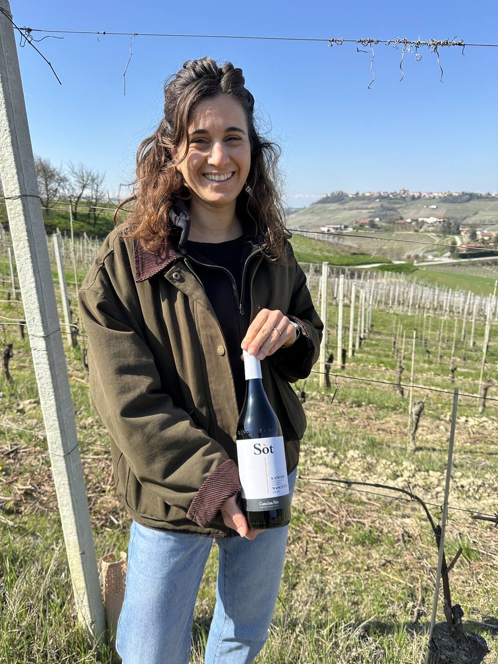Lorena in vigna con una bottiglia